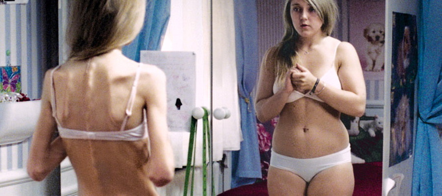 una joven esquelética se mira al espejo y se ve gorda